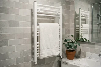 Sèche-serviette électrique vertical blanc fixé sur carrelage gris dans une salle de bain compacte optimisée